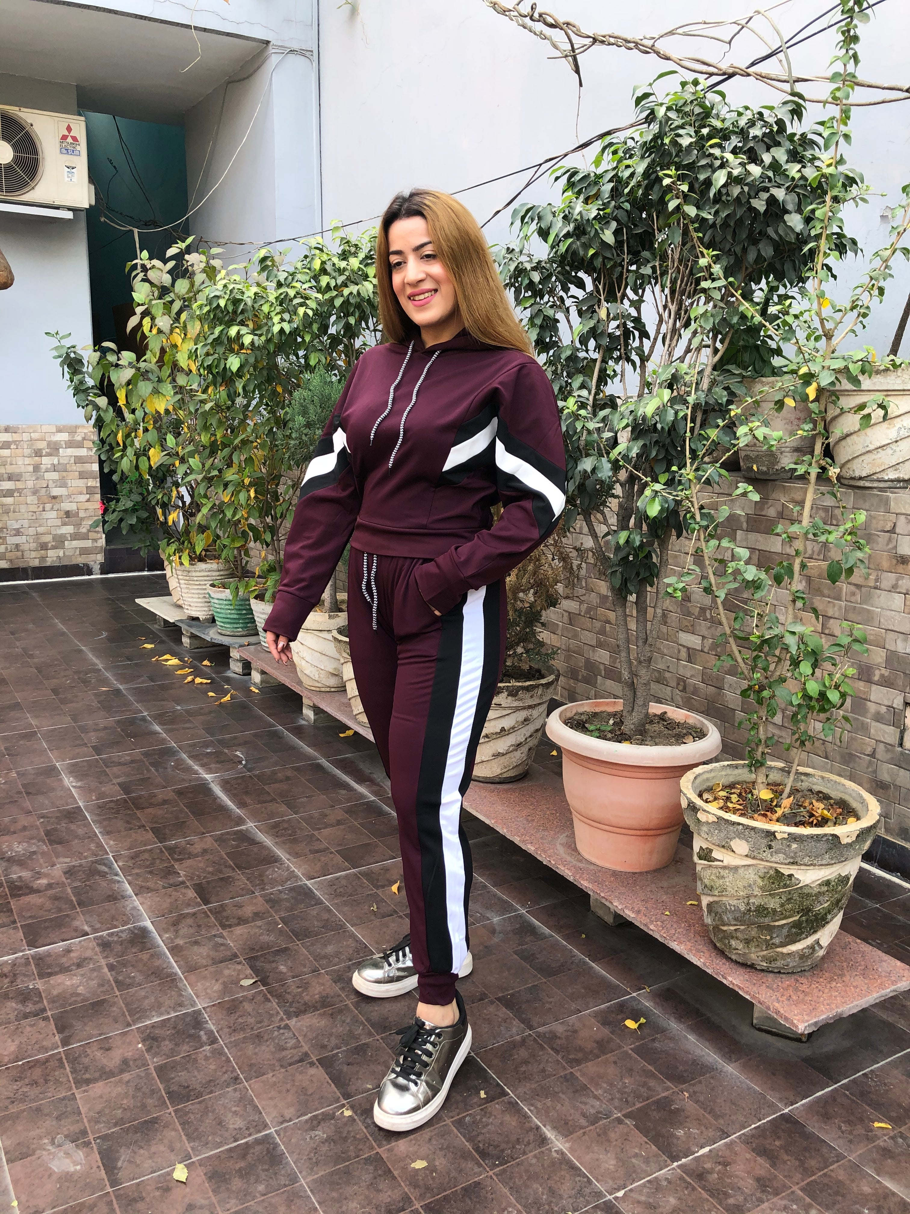 A woman wearing a wine side stripe tracksuit 